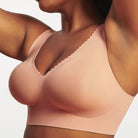 Woman wearing Evelyn & Bobbie Evelyn Bra in Himalayan Salt, light pink no wire pullover bra, against a white background, front view. 