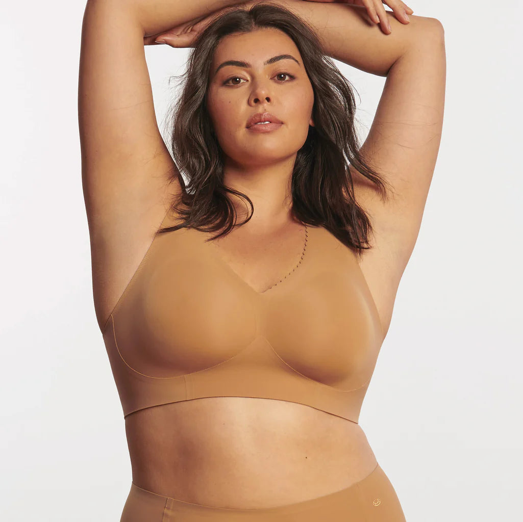 Woman wearing the Evelyn & Bobbie Evelyn Bra in Mica, tan no wire pullover bra, against a white background, front view. 