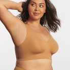 Woman wearing the Evelyn & Bobbie Evelyn Bra in Mica, tan no wire pullover bra, against a white background, front view. 