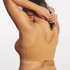 Woman wearing the Evelyn & Bobbie Evelyn Bra in Mica, tan no wire pullover bra, against a white background, back view. 