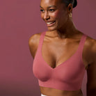 Woman wearing the Evelyn & Bobbie Evelyn Bra in Pink Canyon, dusty pink no wire pullover bra, on a pink background, front view. 