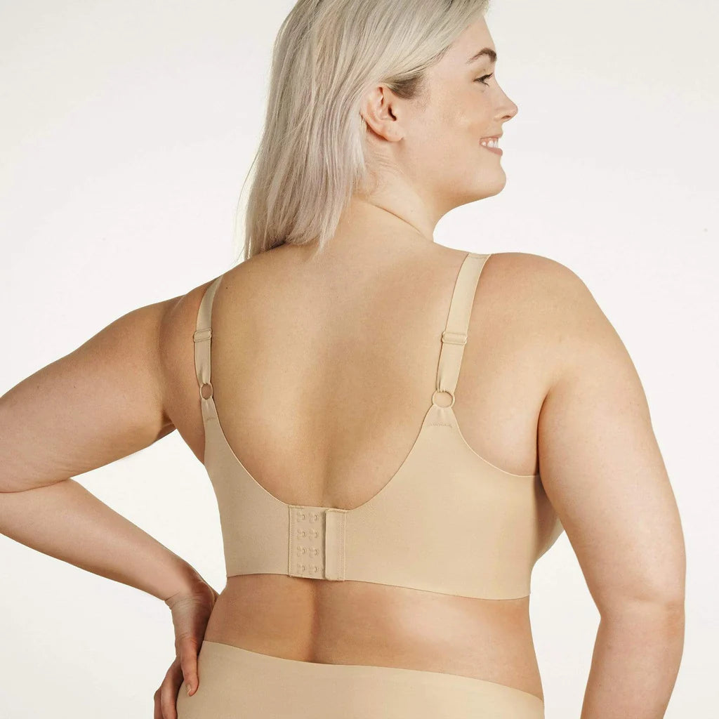 Beyond Bra in Sand, a beige wirefree bra shown on a model from the back view so you can see the adjustable straps and the hook and eye closure back. 