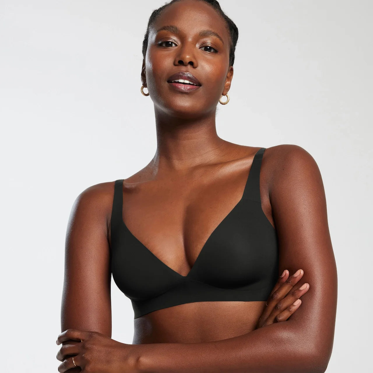 Woman wearing Evelyn & Bobbie Starlette bra in black against a white background. 