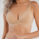 Woman wearing the Evelyn & Bobbie Starlette Bra in Sand, beige no wire bra, against a white background, close up view. 
