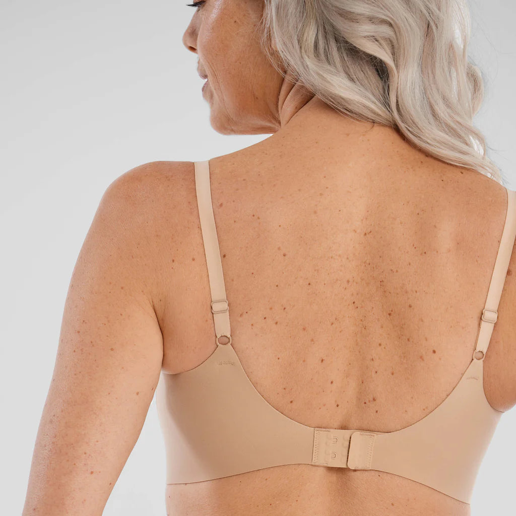 Woman wearing the Evelyn & Bobbie Starlette Bra in Sand, beige no wire bra, against a white background, close up back view. 