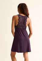 Woman wearing a purple dress with lace detailing on a beige background