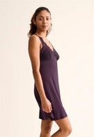 Woman wearing a purple nightgown against a plain background