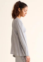 Woman wearing a gray long-sleeve top against a plain background