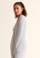 Woman wearing a light gray cardigan over a white top on a beige background