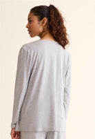 Woman wearing a light gray long-sleeve top on a beige background