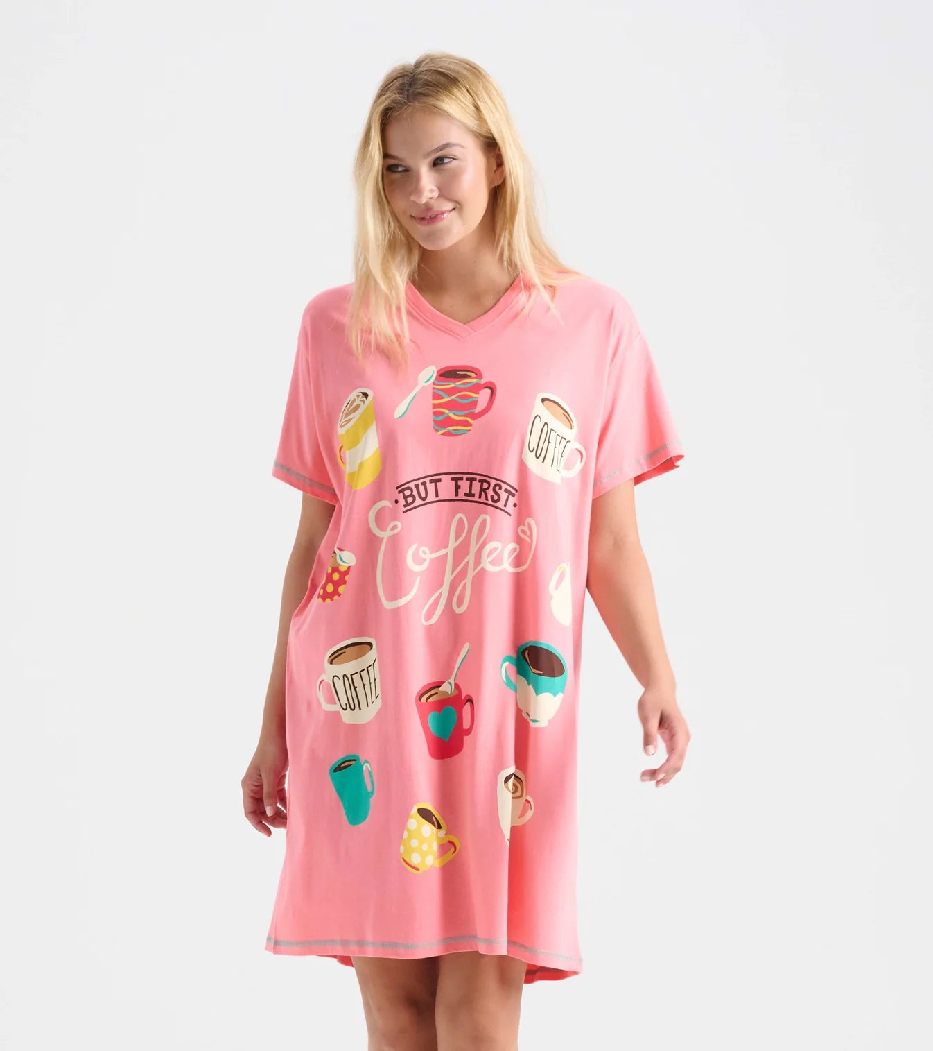 Woman wearing a pink nightshirt with coffee-themed graphics on a white background