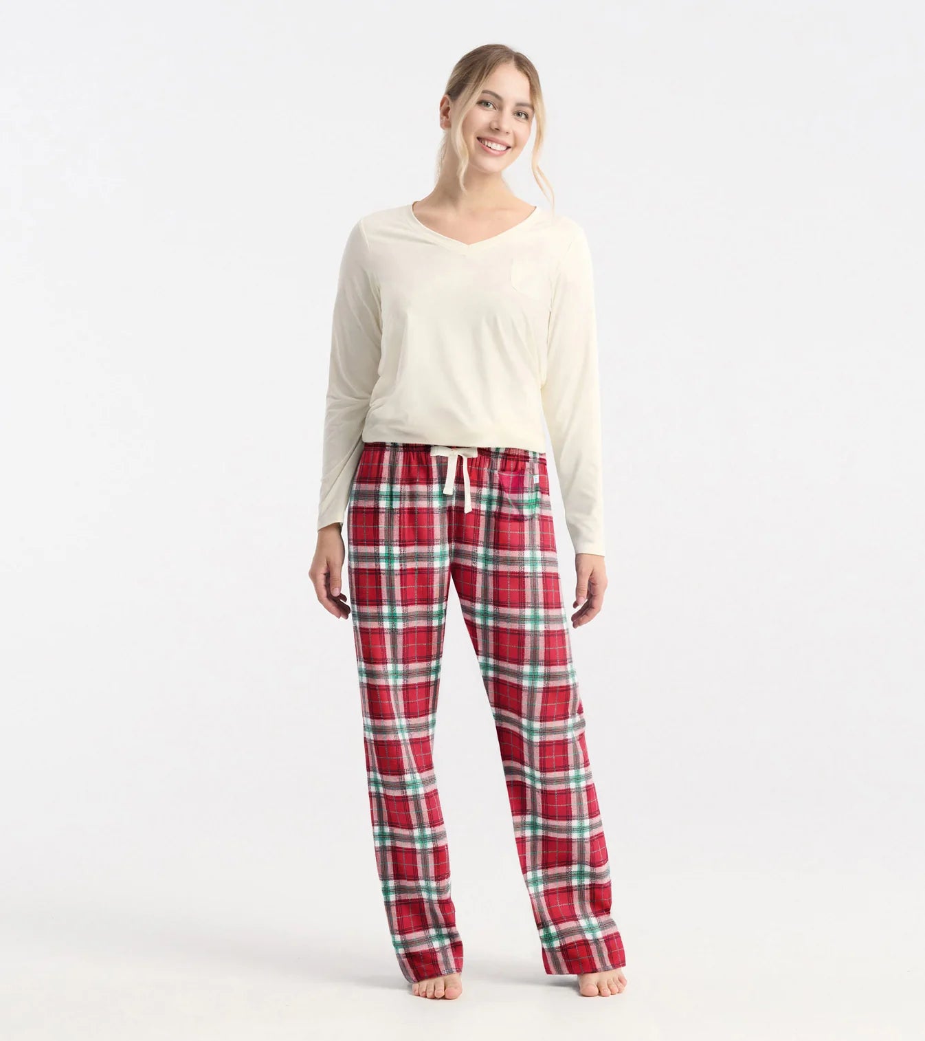 Woman wearing red plaid pajama pants and a white top on a white background