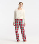 Woman wearing red plaid pajama pants and a white top on a white background