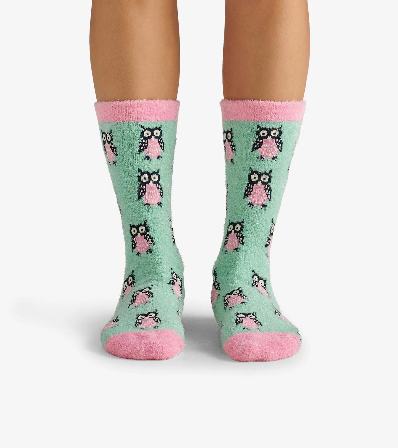 Green socks with pink accents and owl pattern worn by a person on a white background