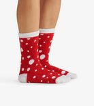 Red socks with white polka dots worn by a person on a white background
