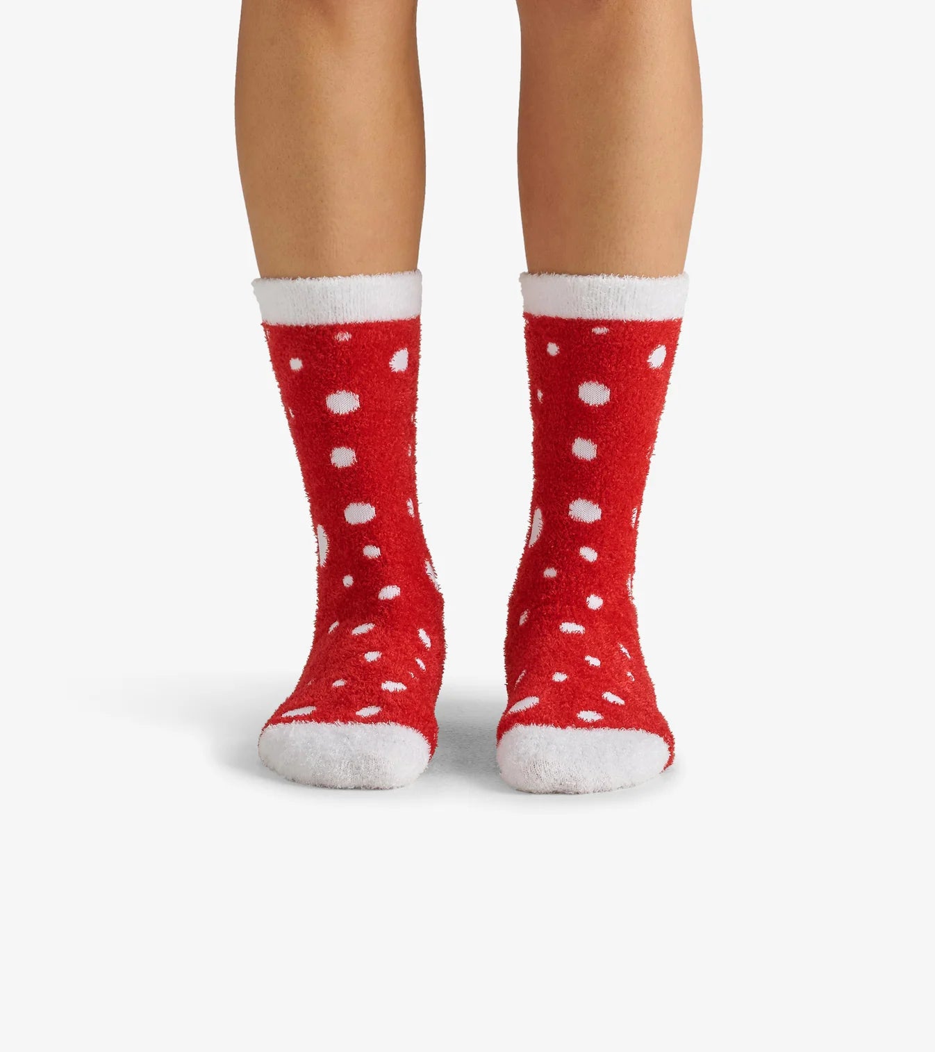 Red socks with white polka dots worn by a person on a white background