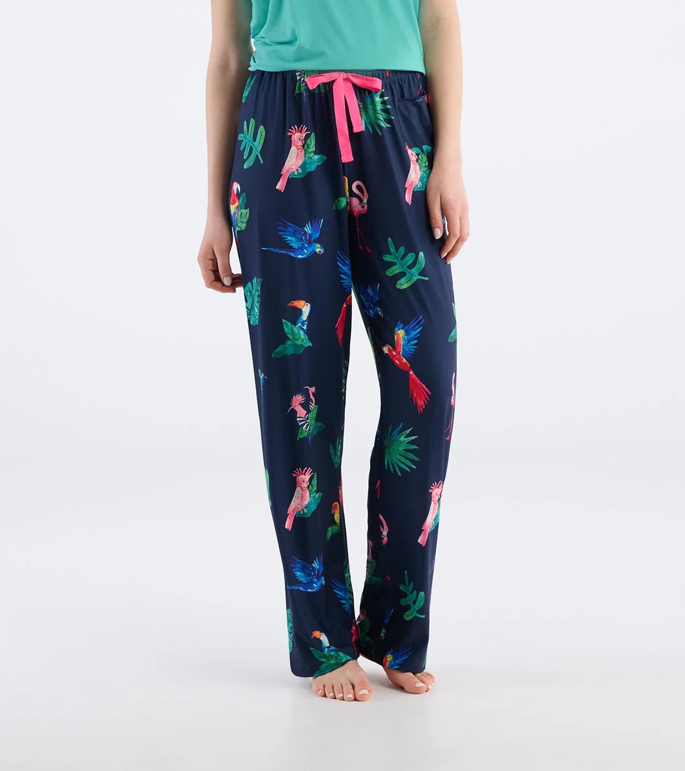 Navy blue pajama pants with colorful parrot pattern worn by a person on a white background