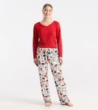 Woman wearing a red top and patterned pajama pants on a white background