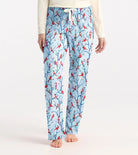 Light blue pajama pants with red bird and branch pattern worn by a person on a white background
