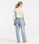 Woman wearing blue pajama pants with bird pattern on a white background