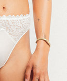 White lace underwear worn by a person on a plain background