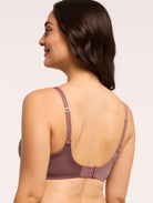 Woman wearing a brown bra against a plain background