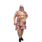 Woman wearing a colorful floral Papa Classic Print dress in Pink against a plain wall.