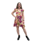Woman wearing a colorful floral Papa Classic Print dress in Pink against a plain wall.