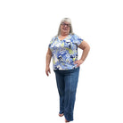 Person wearing a blue floral top and blue Papa Comfort Crop jeans standing against a plain wall, front view. 