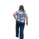 Person wearing a blue floral top and blue Papa Comfort Crop jeans standing against a plain wall, back view. 