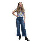 Person wearing a blue floral top and blue Papa Comfort Crop jeans standing against a plain wall, front view. 