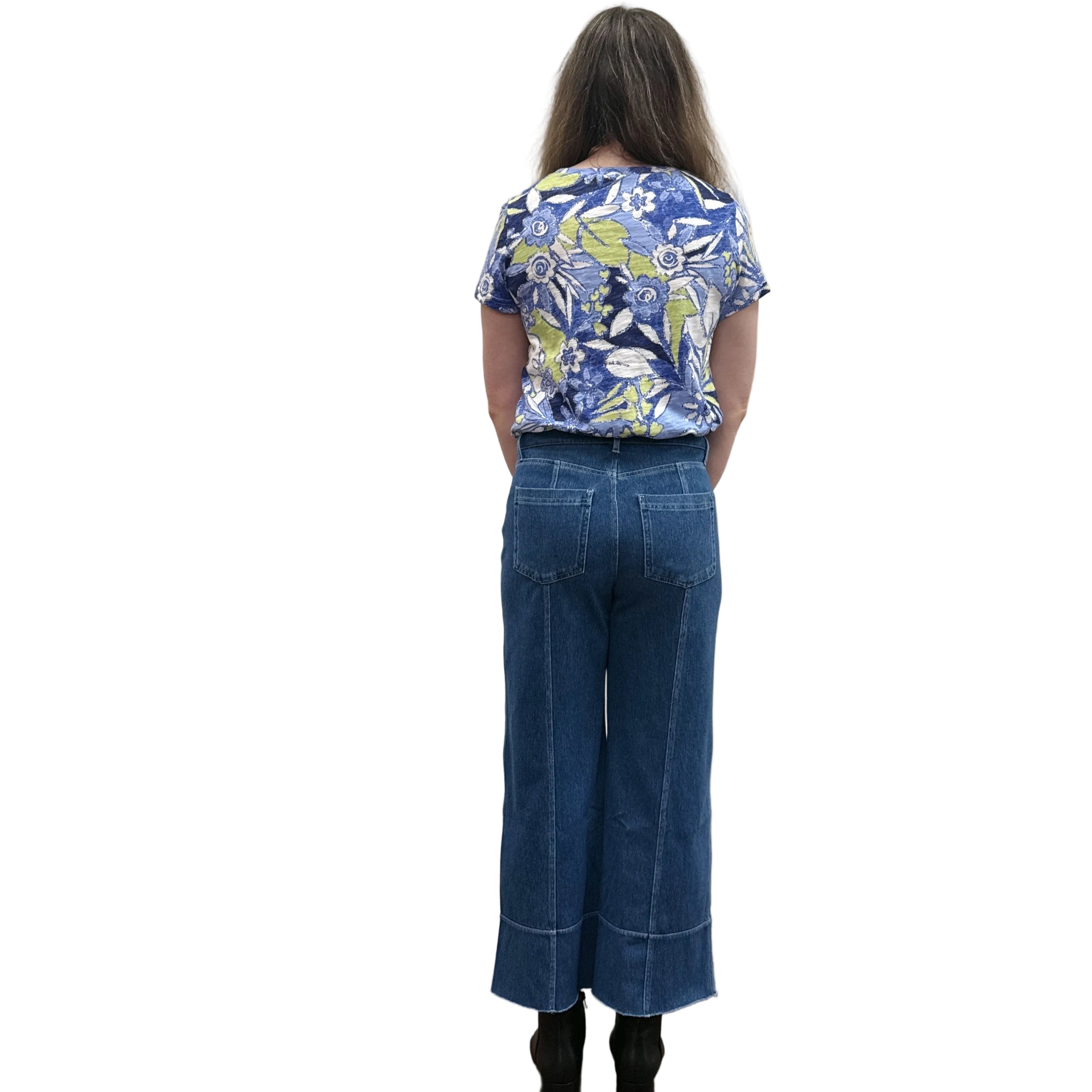Person wearing a blue floral top and blue Papa Comfort Crop jeans standing against a plain wall, back view. 