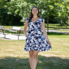 Woman in a floral dress standing in a park with greenery in the background