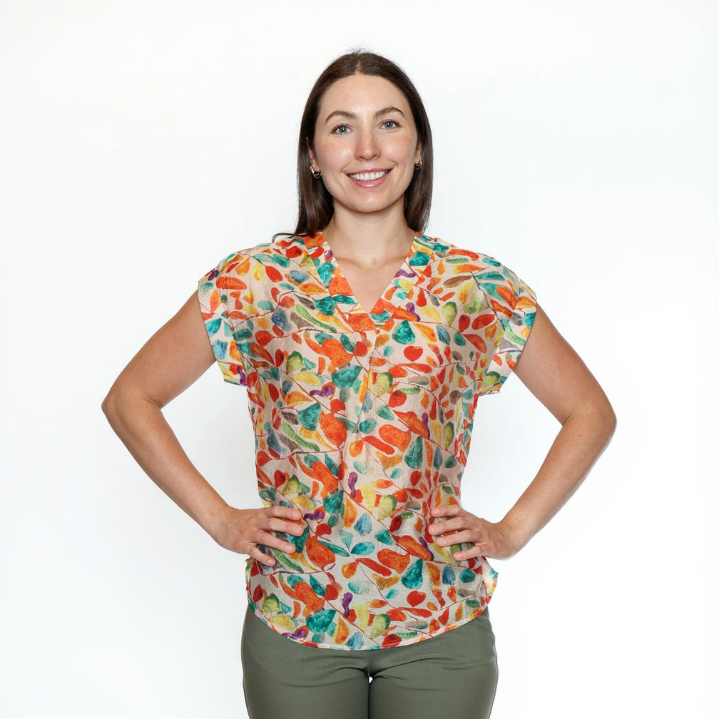 Woman wearing a colorful patterned blouse against a white background