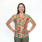 Woman wearing a colorful patterned blouse against a white background