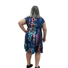 Woman wearing the Papa Indigo Mosaic Breeze patterned dress against a white background, facing the wall to see the back of the dress. 
