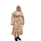 Woman wearing a colorful patterned Papa Saffron Bloom Midi dress against a plain wall.