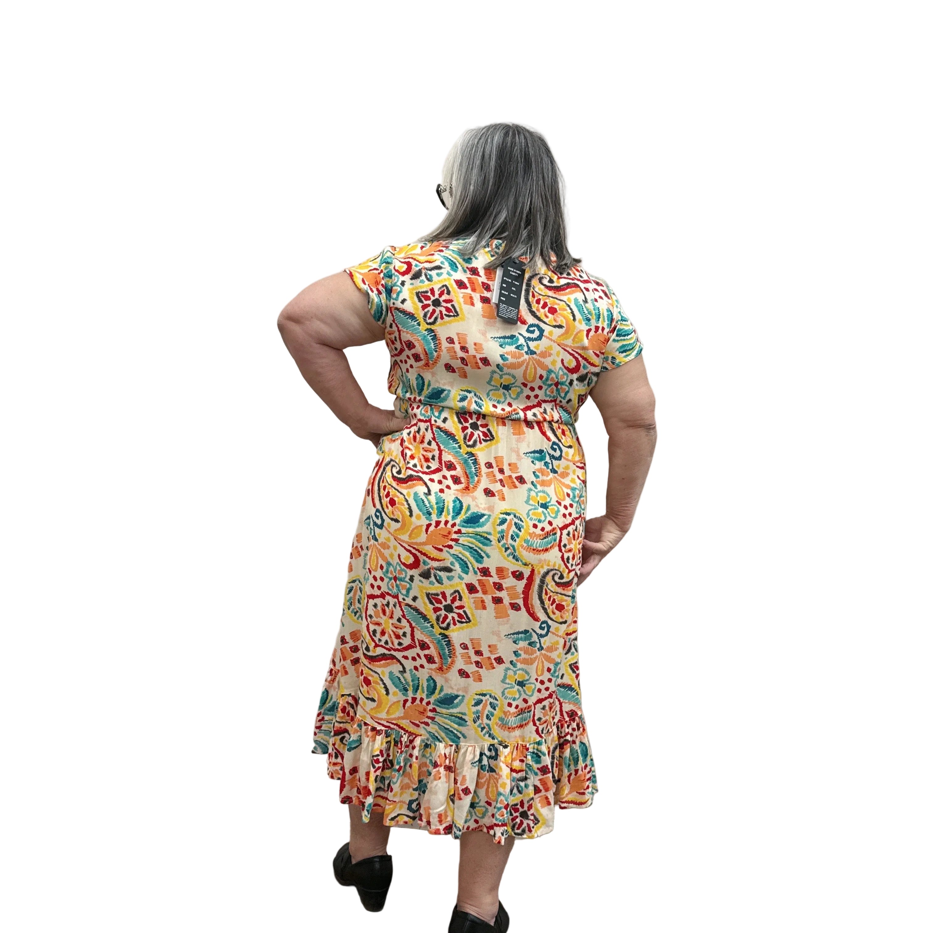 Woman wearing a colorful patterned Papa Saffron Bloom Midi dress against a plain wall facing the back.