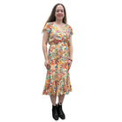 Woman wearing a colorful patterned Papa Saffron Bloom Midi dress against a plain wall.