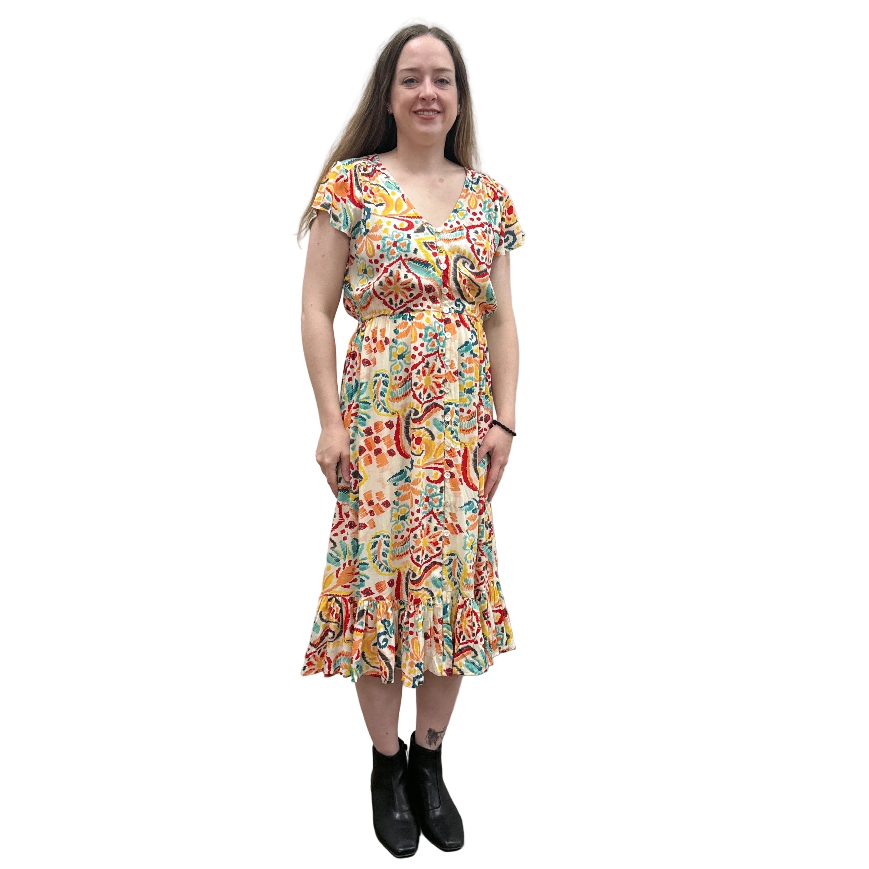 Woman wearing a colorful patterned Papa Saffron Bloom Midi dress against a plain wall.