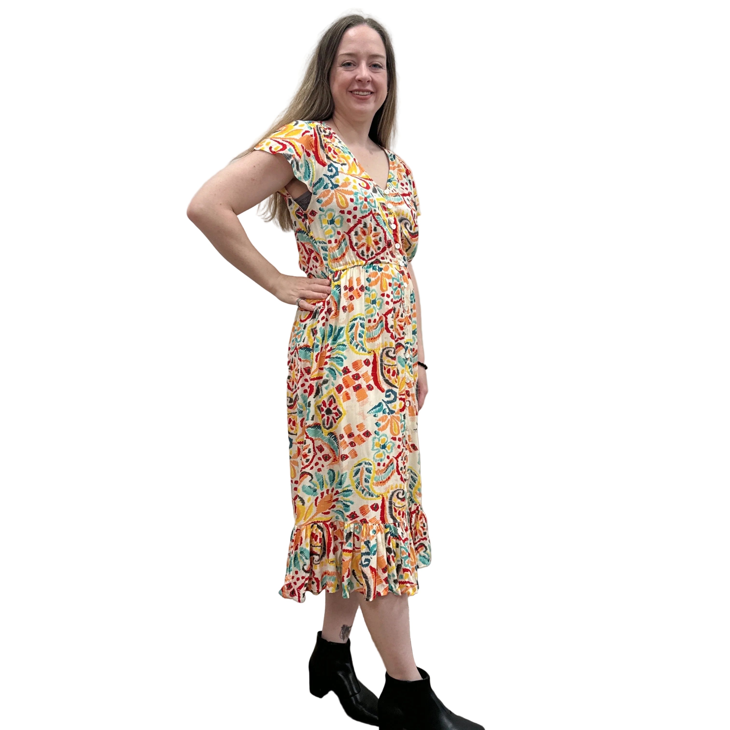 Woman wearing a colorful patterned Papa Saffron Bloom Midi dress against a plain wall.