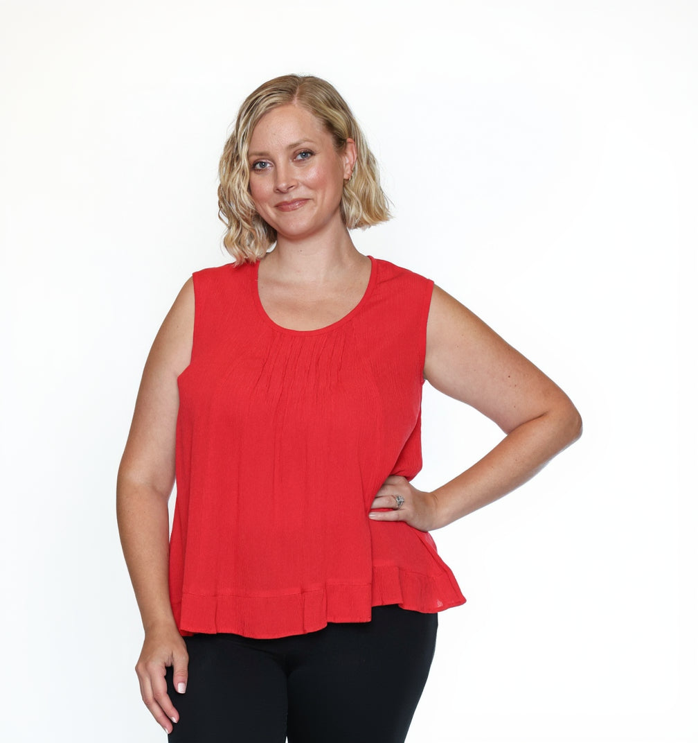 Woman wearing a red sleeveless top and black pants on a white background