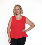 Woman wearing a red sleeveless top and black pants on a white background