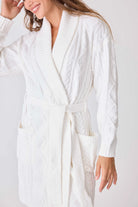 Woman wearing a white textured robe on a plain background