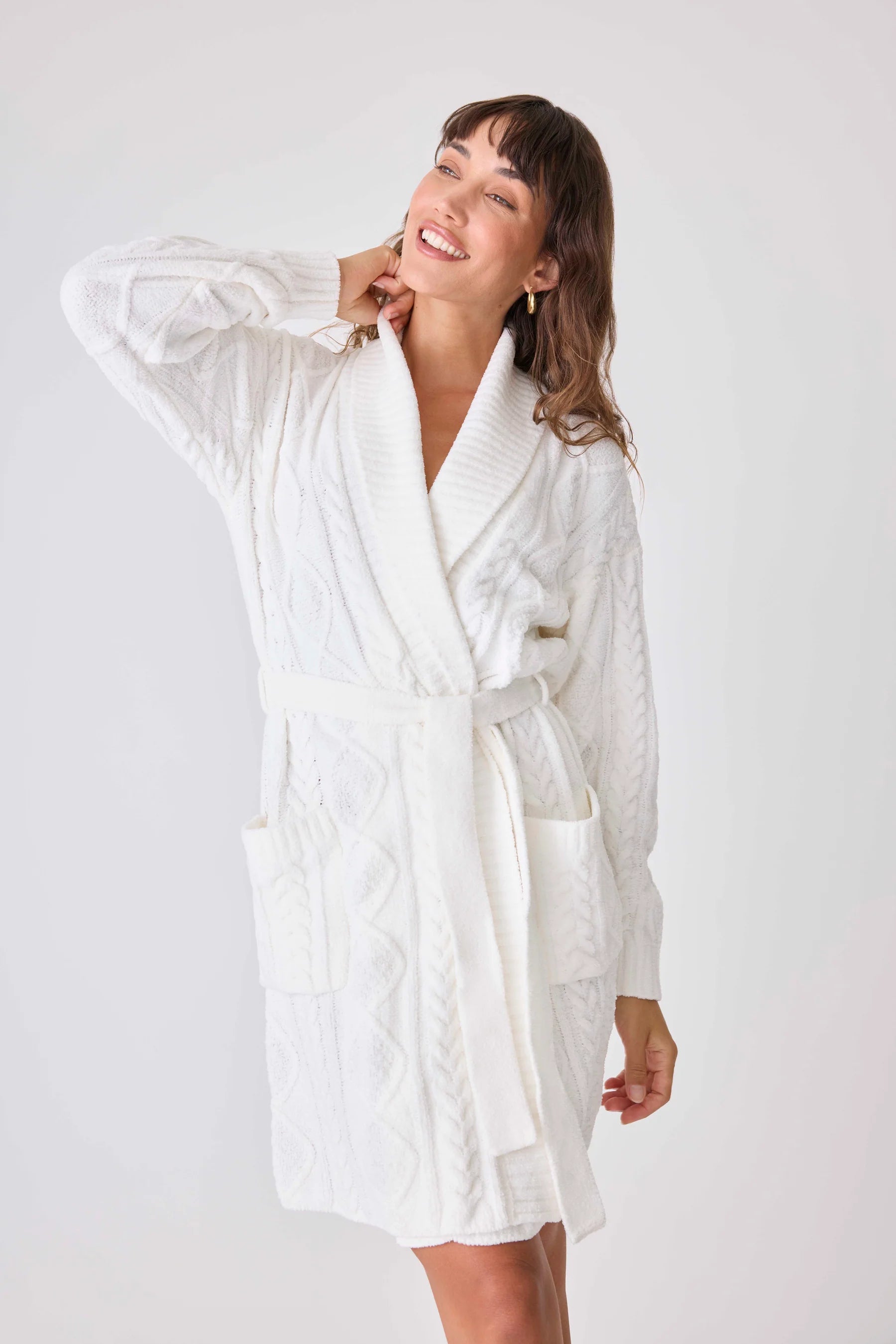 Woman wearing a white robe against a plain background