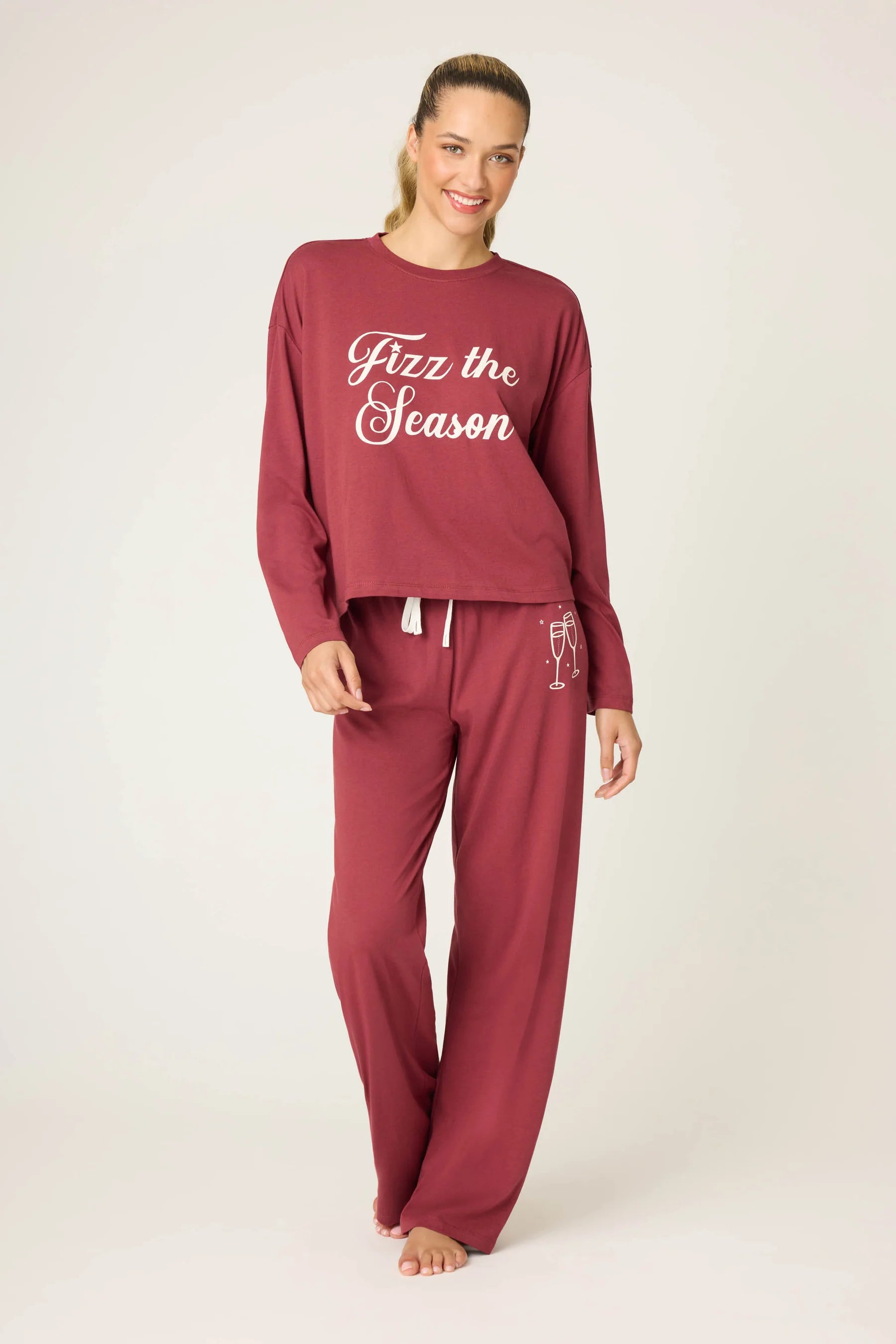 Woman wearing a burgundy pajama set with 'Fizz the Season' text on a white background