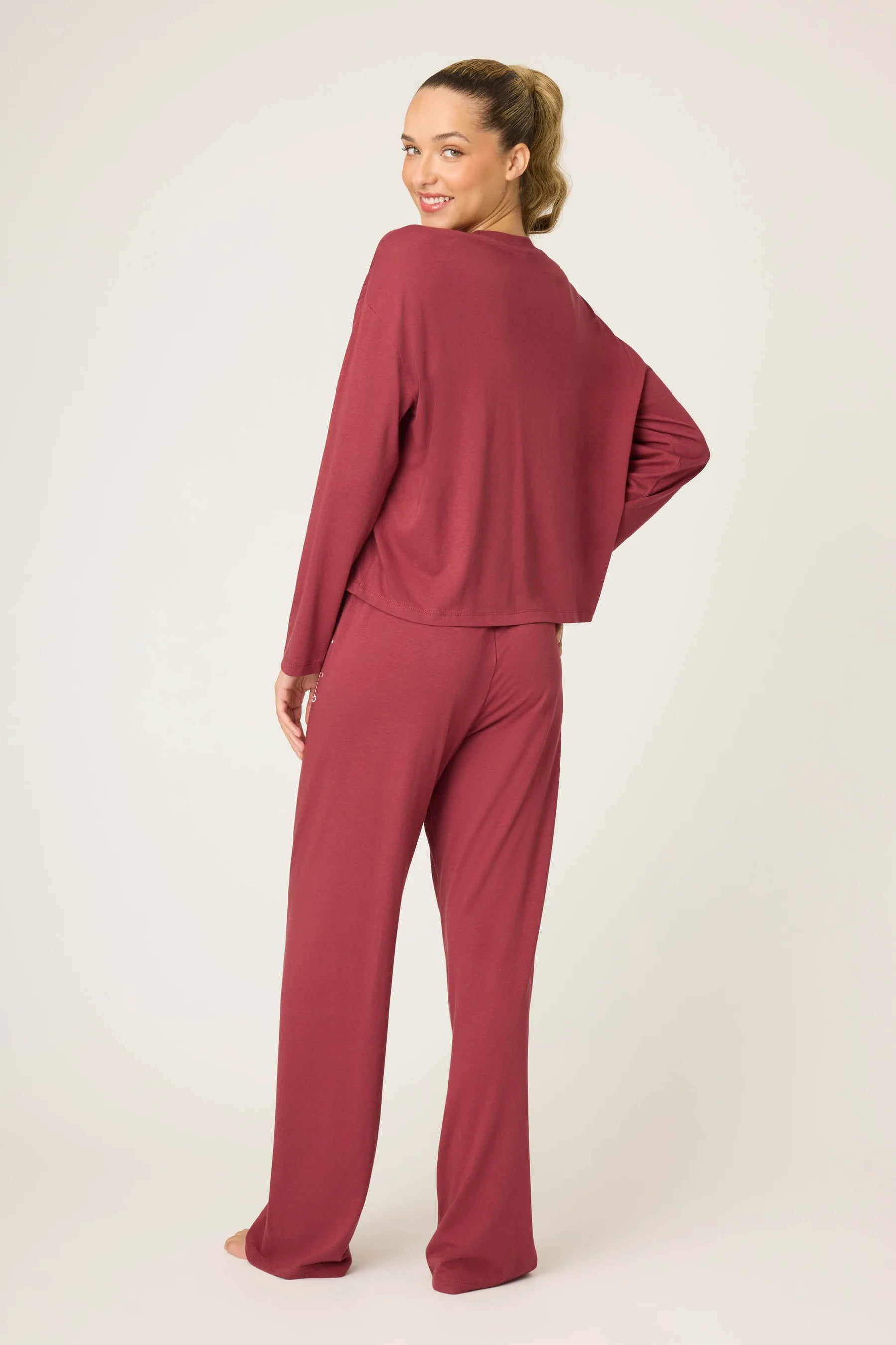 Woman wearing a burgundy loungewear set on a white background