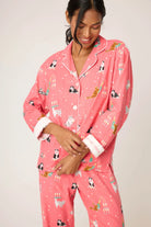 Woman wearing pink pajamas with animal prints on a plain background
