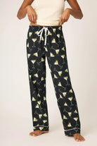 Black pajama pants with cocktail pattern worn by a person on a white background