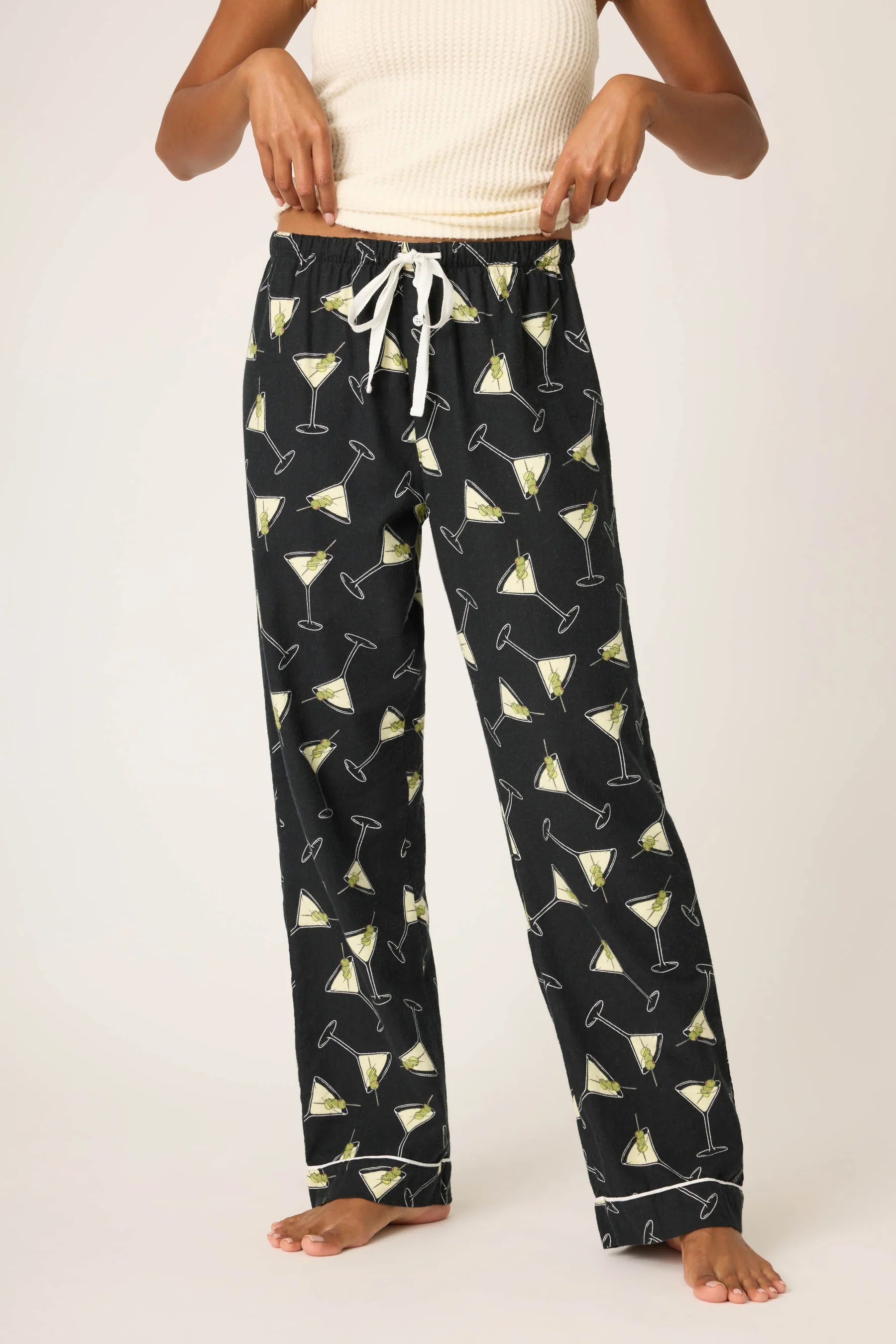 Black pajama pants with cocktail pattern worn by a person on a white background